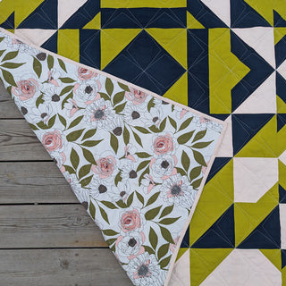 Close-up of a modern geometric quilt with olive green, navy, and cream colors, showing floral backing; design made using The 279 Quilt Pattern (Download) by Millie & Bun Designs.
