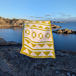 The 2995 Quilt Pattern by Millie & Bun Designs features a modern geometric design in mustard yellow and white, perfect for confident beginner quilters.