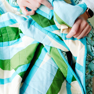 Close-up of colorful quilt made with blue, green, and white fabric held by hands, showcasing the Alderbrook Quilt Pattern (Download) by Julia Wachs Designs.