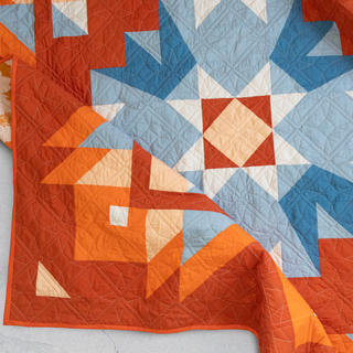 Close-up of a vibrant orange and blue geometric quilt showcasing detailed stitching, highlighting the Aria Quilt Pattern (Download) by Toad & Sew.
