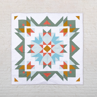 Aria Quilt Pattern (Download) by Toad & Sew featuring a geometric, modern design with green, orange, blue, and white shapes in a bold star medallion quilt pattern.