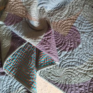 Close-up of a quilt featuring intricate curved quilting and muted earth tones, showcasing craftsmanship related to the Vault Quilt Pattern (Download) by Urban Dwell Studio.