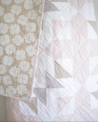 Closeup of a soft neutral quilt featuring geometric and floral patterns, showcasing detailed stitches, from Sewn’s Bedroom Quilt Pattern (Download).