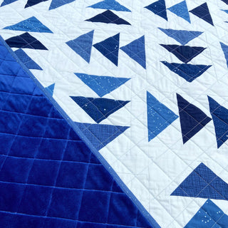 Blue and white geometric quilt with triangular patchwork and quilted navy backing from Homemade Emily Jane. Blessings Quilt Pattern (Download)