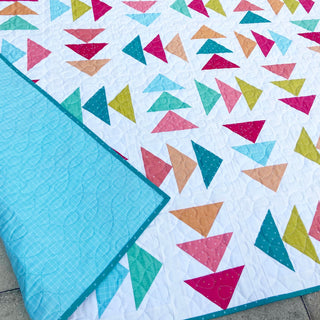 Blessings Quilt Pattern (Download) by Homemade Emily Jane featuring a colorful geometric quilt with teal pink coral and mustard triangles on white fabric