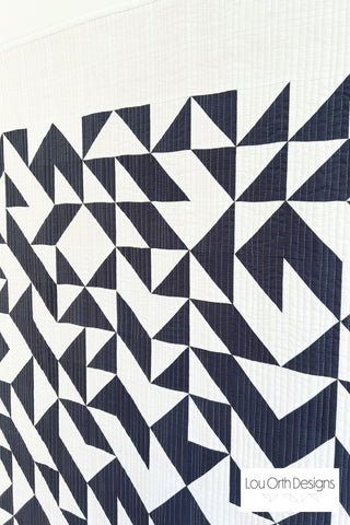 Close-up of a modern black and white geometric quilt showcasing the Break Away Quilt Pattern (Download) by Lou Orth Designs with detailed stitching and sharp triangle shapes.