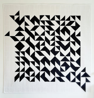 Modern black and white quilt featuring geometric shapes and half square triangles, designed by Lou Orth, showcasing the Break Away Quilt Pattern (Download).