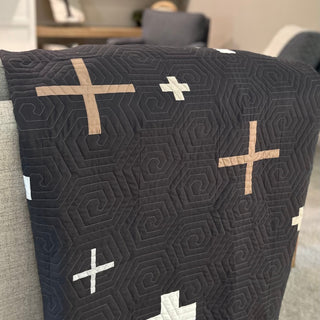 Close-up of a modern quilt featuring geometric spiral quilting and tan and white cross shapes, made using the Callie Quilt Pattern (Download) by Sew & Sew Quilting Co.