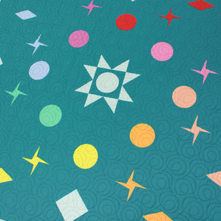 Close-up of a colorful quilt with star and circle shapes on a teal background, showcasing the Celestial Quilt Pattern (Download) by Lou Orth Designs.