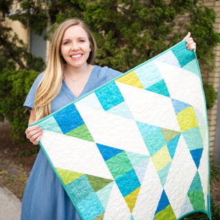 Cirrus Quilt Pattern (Download) by Homemade Emily Jane shown as a modern geometric quilt with airy white shapes and bright blue green and yellow fabric accents