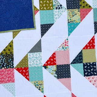 Cirrus Quilt Pattern (Download) by Homemade Emily Jane featuring a modern geometric quilt with airy white pathways and colorful patterned fabric triangles