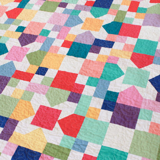 Close-up of a colorful geometric quilt featuring various shapes and pastel shades, showcasing the Confetti Garden Quilt Pattern (Download) by Straight Stitching.