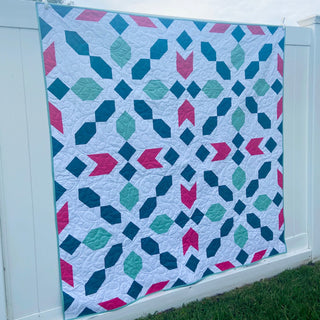 Connector Quilt Pattern (Download) by Homemade Emily Jane, colorful modern geometric quilt with teal, blue, pink, and aqua shapes displayed outdoors