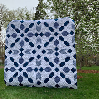 Connector Quilt Pattern (Download) by Homemade Emily Jane featuring a modern blue and white geometric quilt with chain-like blocks displayed outdoors