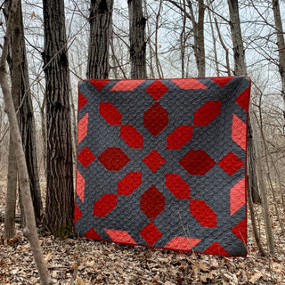 Connector Quilt Pattern (Download) by Homemade Emily Jane modern geometric red and charcoal quilt displayed in a woodland setting