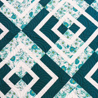 Close-up of a teal and white floral quilt pattern featuring geometric shapes and curved quilting stitches, showcasing the Coreina Quilt Pattern (Download) by A Piece of Quiet Quilts.