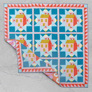 Colorful quilt featuring house and geometric star blocks in bright blues, pinks, and yellows, made using the Cottagecore Quilt Pattern (Download) by Toad & Sew.