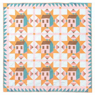 Bright quilt featuring repeating house and star blocks in orange, teal, brown, and pink, showcasing the Cottagecore Quilt Pattern (Download) by Toad & Sew.