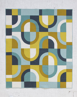 Geometric patterned Currents quilt by Eudaimonia Studio with blue, yellow, and white colors on a light gray background