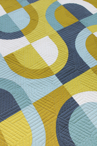 Close-up of the Currents quilt by Eudaimonia Studio with geometric circular patterns in blue, yellow, and white.