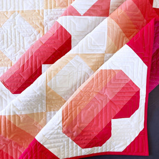 Close-up of a modern quilt with gradient heart blocks in warm tones, showcasing detailed quilting from Penny Spool Quilts using the Dancing Hearts Quilt Pattern (Download).