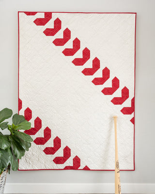 Fastball 2.0 Quilt Pattern (Download) by Jessica Steele Design featuring a modern white quilt with bold red baseball inspired geometric accents and a bat