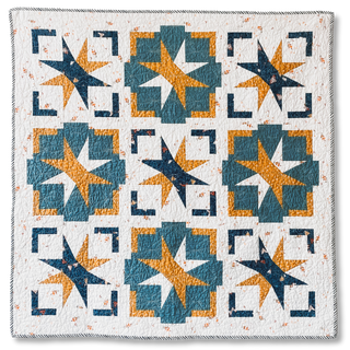 Colorful star and geometric block quilt with blue, orange, and white tones, showcasing the Festive Gala Quilt Pattern (Download) by A Piece of Quiet Quilts.