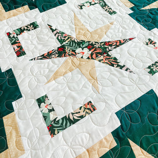 Festive Gala Quilt Pattern by A Piece of Quiet Quilts closeup: teal, tan, and white star block with floral center fabric and circle quilting on background.