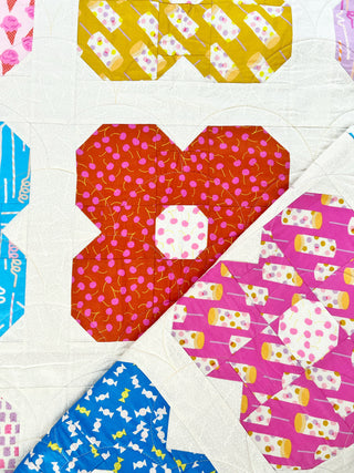 Close-up of colorful floral quilt blocks with playful patterns, showcasing detailed stitching from Lou Orth Designs' Flower Friends Quilt Pattern (Download).