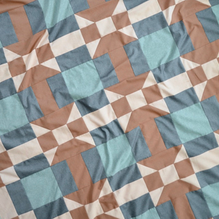 Close-up of a modern geometric quilt in teal, brown, and cream colors, showcasing the Footpath Quilt Pattern (Download) by Sewn with clean lines and precise piecing.