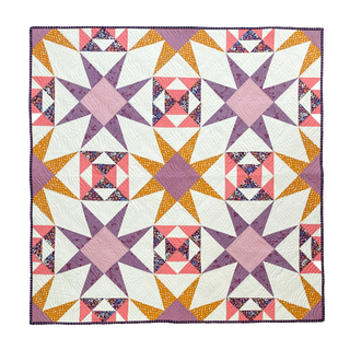Colorful geometric quilt with star and block patterns in purple, pink, orange, and white, showcasing the Freya June Quilt Pattern (Download) by A Piece of Quiet Quilts.