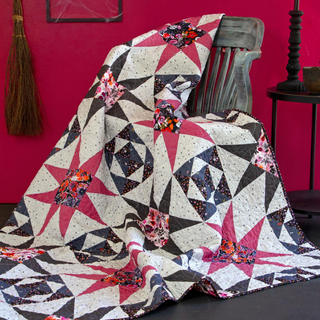 Freya June Quilt Pattern (Download) by A Piece of Quiet Quilts features a modern geometric design with dark, pink, and floral fabric pieces, perfect for confident beginner quilters.