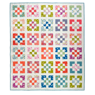 Colorful patchwork quilt with floral and geometric prints arranged in a grid pattern, showcasing the Front Street Quilt Pattern (Download) by A Piece of Quiet Quilts.