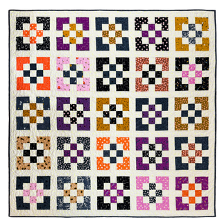 Colorful patchwork quilt featuring geometric block patterns in purple, orange, black, and mustard on a white background made using Front Street Quilt Pattern (Download) by A Piece of Quiet Quilts.