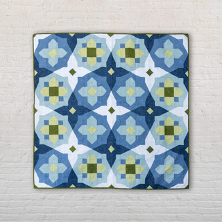 A modern quilt in shades of blue and green with geometric floral shapes, showcasing the Garden Glow Quilt Pattern (Download) by Toad & Sew.
