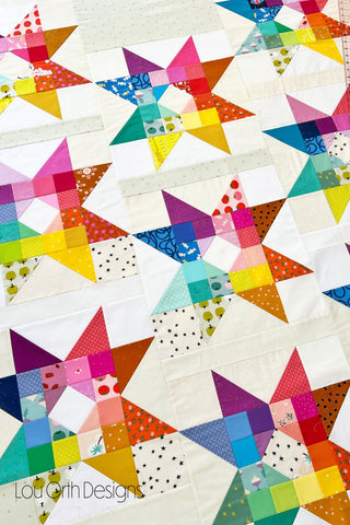Close-up of colorful star quilt blocks with varied patterns and fabrics arranged on a white background by Lou Orth Designs, shown for Gemburst Quilt Pattern (Download).