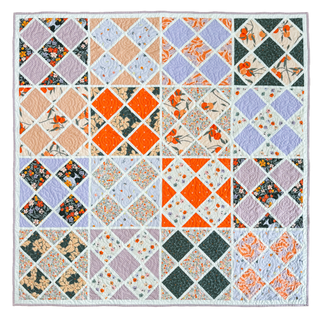 Colorful quilt featuring floral and geometric patterns in orange, purple, and cream, showcasing the Harlequin Bloom Quilt Pattern (Download) by A Piece of Quiet Quilts.