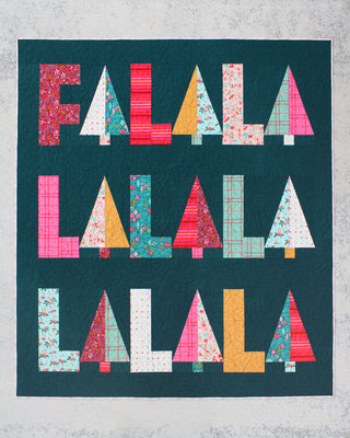 Fa-La-La Quilt Pattern (Download) by Patternly Collective showing a colorful holiday quilt with bold patchwork letters on a dark teal background