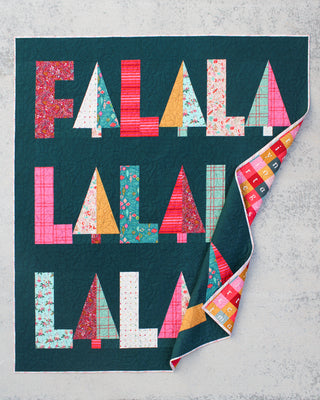 Fa-La-La Quilt Pattern (Download) by Patternly Collective showing a colorful holiday quilt with bold Fa La La lettering on a deep teal background