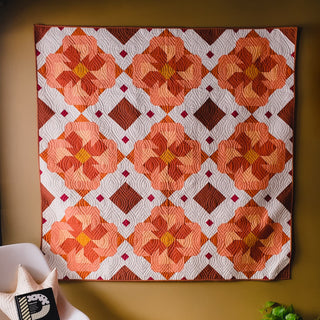 Colorful flower-inspired quilt with warm orange and red tones in a geometric pattern, created using the Ixora Quilt Pattern (Download) by Thai Charm.