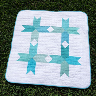 Limelight Quilt Pattern (Download) modern geometric quilt in aqua and white with bold negative space displayed on grass by Homemade Emily Jane