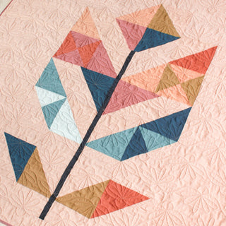 Close-up of a colorful geometric leaf quilt pattern with intricate floral quilting on a light background, showcasing the May Quilt Pattern (Download) by Month of May Quilting.
