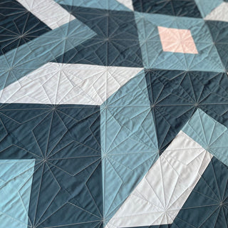 Mt. Pisgah Quilt Pattern by Hampton Quilt Studio quilting detail: closeup of teal, blue, white, and pink triangle and diamond blocks with visible quilting stitches.