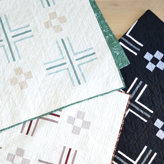 Three geometric quilts in neutral tones and soft greens and blues, showcasing the Mudroom Quilt Pattern (Download) by Sewn with a modern, clean design.