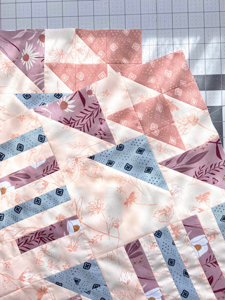 Quilt with patterned fabric triangles on a grid background