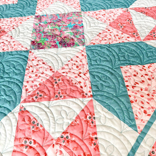 Close-up of a detailed quilt featuring pinks, teals, and floral patterns with intricate quilting by Shadow Valley Quilts using the Northern Glow Quilt Pattern (Download).