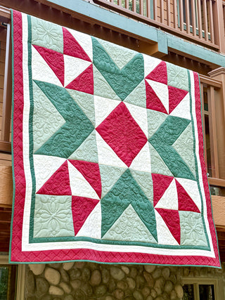 Quilt featuring red, green, and white geometric patterns with intricate stitching, showcasing the Northern Glow Quilt Pattern (Download) by Shadow Valley Quilts.