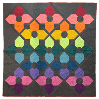 Colorful geometric flower quilt with vibrant pink, orange, yellow, green, blue, and purple petals on a gray background, showcasing the Orchid Garden Quilt Pattern (Download) by A Piece of Quiet Quilts.