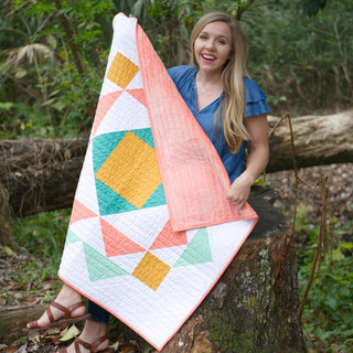 Paradigm Quilt Pattern (Download) by Homemade Emily Jane featuring a colorful modern geometric quilt with coral teal yellow and white shapes displayed outdoors