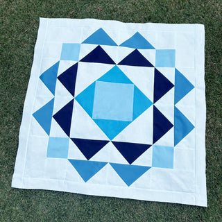 Paradigm Quilt Pattern (Download) by Homemade Emily Jane featuring a bold geometric blue and white quilt design with dynamic repeating shapes on grass